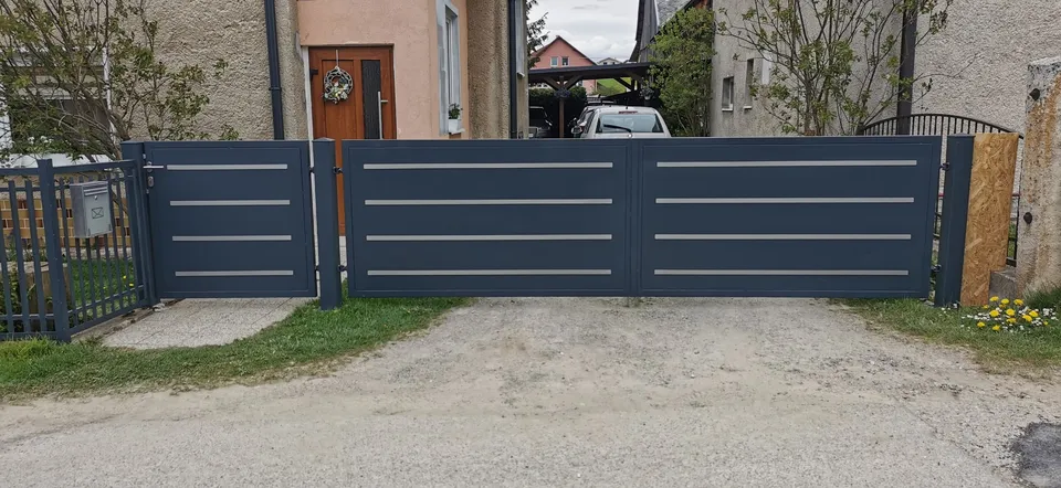 Antracitová brána a bránka s vodorovnými pásmi pred rodinným domom