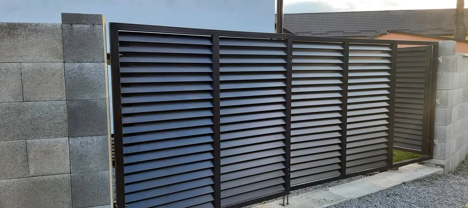 Tmavá žalúziová brána medzi tvárnicovými stĺpmi
